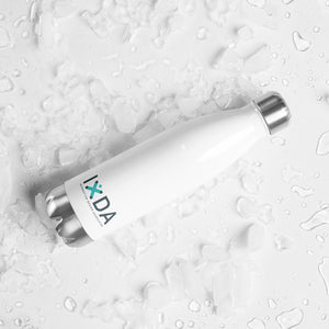 white stainless steel water bottle on it's side on a white surface. IxDA logo in teal and grey on lower part of the bottle.  