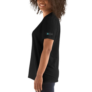Woman from the side wearing black T-shirt with teal and grey IxDA logo on the left sleeve.  