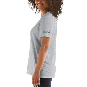 Woman from the side wearing sport grey T-shirt with teal and grey IxDA logo on the left sleeve.  