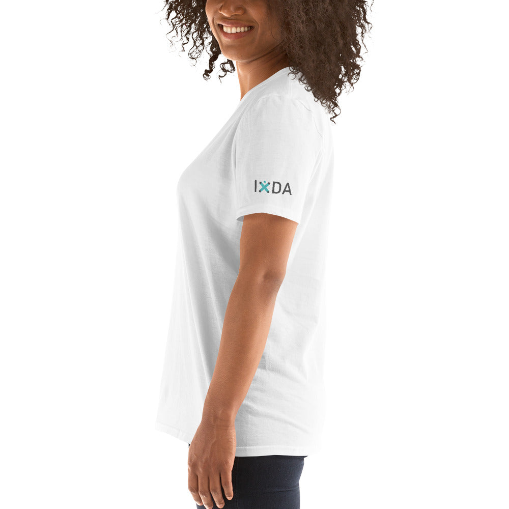 Woman from the side wearing white T-shirt with teal and grey IxDA logo on the left sleeve.  